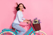 Photo of impressed dreamy young woman wear white sweater driving bike wind blowing smiling isolated pink color background