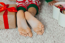 Close-up Child's Bare Feet On His Knees Near The Christmas Tree With Christmas Balls. New Year Winter Concept. ...