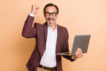 Sticker - Portrait of attractive cheerful lucky man using laptop rejoicing having fun great profit isolated over beige color background