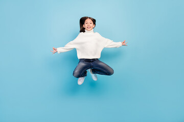 Poster - Photo of funny charming student girl wear white sweater smiling jumping high isolated blue color background