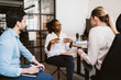 © Maskot - Mid adult businesswoman explaining while discussing with male and female colleagues in creative office