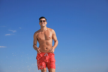 Wall Mural - Handsome man with attractive body against blue sky