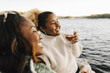 © Maskot - Smiling woman enjoying wine with female friend at lakeshore