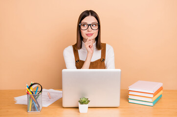 Wall Mural - Portrait of attractive pensive skilled girl employee using laptop it start up analyse isolated over beige color background