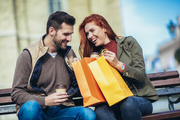 Portrait of happy couple with shopping bags after shopping in city smiling