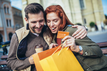 Wall Mural - Portrait of happy couple with shopping bags after shopping in city smiling and holding credit card