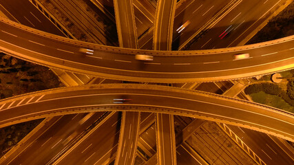 Canvas Print - Aerial drone long exposure night photo of urban elevated road junction and interchange overpass in city with light traffic
