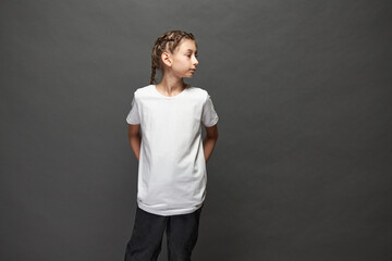 Kid girl wearing white t-shirt with space for your logo or design in studio over gray background