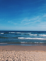 Wall Mural - Vertical shot of soft ocean waves with foam on a sandy beach