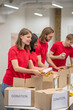 © zinkevych - Young peeple in red packing the cardboards with humanitarian help