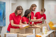 © zinkevych - Young peeple in red packing the cardboards with humanitarian help