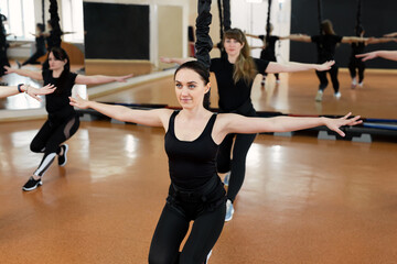 Wall Mural - Group of active sports girls in black sportswear are engaged in budgie fitness in the gym. Bungee jumping in the gym