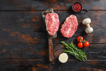 Wall Mural - Organic Top blade  steak, raw meat, marbled beef butler cut on metal butcher cleaver knife with rosemary and farm herbs over old wood table background top view space for text