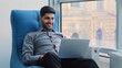 © Yuliia - Happy millennial Indian corporate employee in creative profession sits in comfortable armchair in coworking space using computer. Young Arabic professional working on laptop, dreaming, create new idea