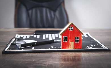 Wall Mural - Wooden house model and pen on financial graphs.