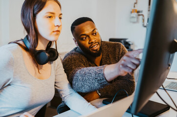 Male hacker discussing with female colleague over computer in startup company