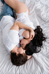 Wall Mural - overhead view of man in jeans hugging sexy woman in shirt and panties on bed