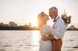 Fototapeta Tulipany - Happy elderly couple in wedding dress looking at each other in sun.