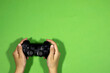 © hadjanebia - hands holding a black joystick, game controller isolated on green background