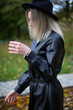 © PIXbank - White young european woman with blonde hair in park in autumn black raincoat