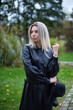 © PIXbank - Blond young woman in autumn black raincoat in park