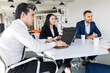 © xartproduction - Group of young business people working and communicating while sitting at the office desk together with colleagues sitting. business meeting