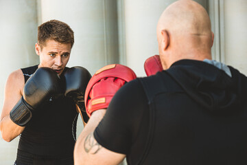 Poster - Two men exercising and fighting in outside. Boxer in gloves is training with a coach