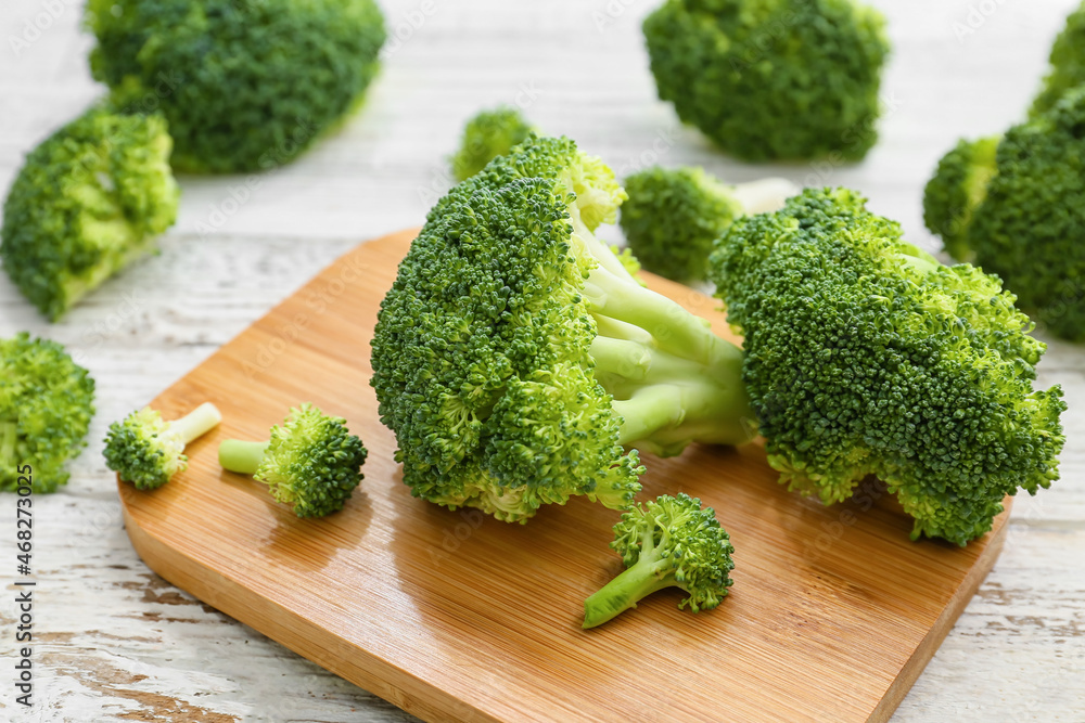 Board with healthy broccoli cabbage on light wooden background