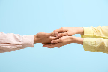 Wall Mural - Woman holding man's hand on blue background