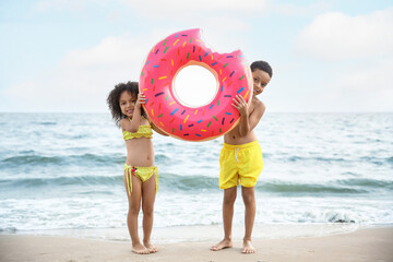 Poster - African-American children with inflatable ring on sea beach