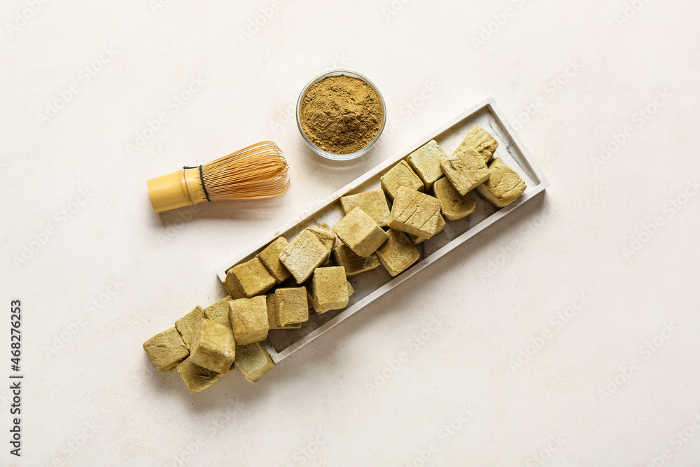 Plate with tasty hojicha marshmallows, powder and chasen on light background