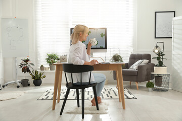 Sticker - Woman with cup of tea at table in light room. Home office