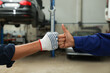 Mechanics making fist bump at automobile repair shop, closeup