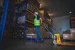 © chokniti - Handsome young male employee concentrating and focusing on work wearing safety helmet and uniform in warehouse while standing between racks in aisle