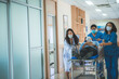 © chokniti - a group of medics or doctors carrying male patient on hospital gurney to emergency or operation room, urgent caseon  gurney being pushed at speed through a hospital.