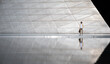 © chokniti - Young hipster man with hat and casual clothing holding brown bag walking against white installation wall and looking away with reflection falling downwards