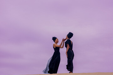 Poster - Two woman seen standing on top of sand dune