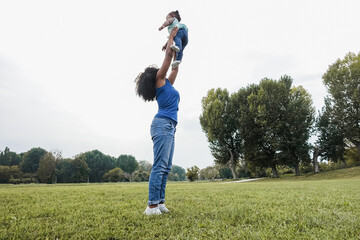 Happy black mother playing with her daughter outdoor at park city