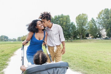 Wall Mural - Happy black family having fun walking with stroller outdoor at city park - Soft focus on woman face