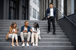 © rh2010 - Multiracial business team talking and using digital devices on stairs in city. Concept of business cooperation. Idea of remote and freelance work. Modern successful business people in formal wear