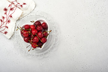 Cherry with water drops on heart shaped plate on white stone table. Fresh ripe cherries. Sweet red cherries. Top view. Rustic style. Fruit Background