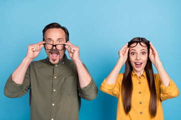 Poster - Portrait of two astonished impressed persons hands touch eyewear open mouth isolated on blue color background