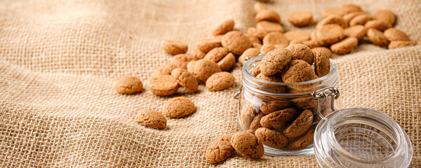 Banner with kruidnoten cookies in glass jar on sackcloth. Pepernoten, traditional sweets, strooigoed. Dutch holiday Sinterklaas Saint Nicholas day concept of with copy space.