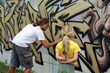 Blondes Mädchen schaut Graffiti Sprüher an der Wand zu