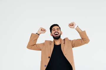 Wall Mural - Successful man celebrating with arms up isolated over gray background