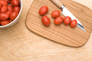 Sticker - datterini tomatoes in a bowl with chopping board and knife on a  rustic wooden background