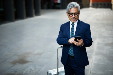 Wall Mural - Senior businessman outdoors. Middle-aged businessman using the phone.