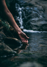 Vertical Shot Of A Person Touching The Water Of A Creak