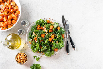 Healthy vegan salad with roasted sweet potato and kale on grey concrete background, table top view with copy space