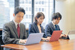 © rrice - ノートパソコンで仕事をする３人の男女のビジネスマン
